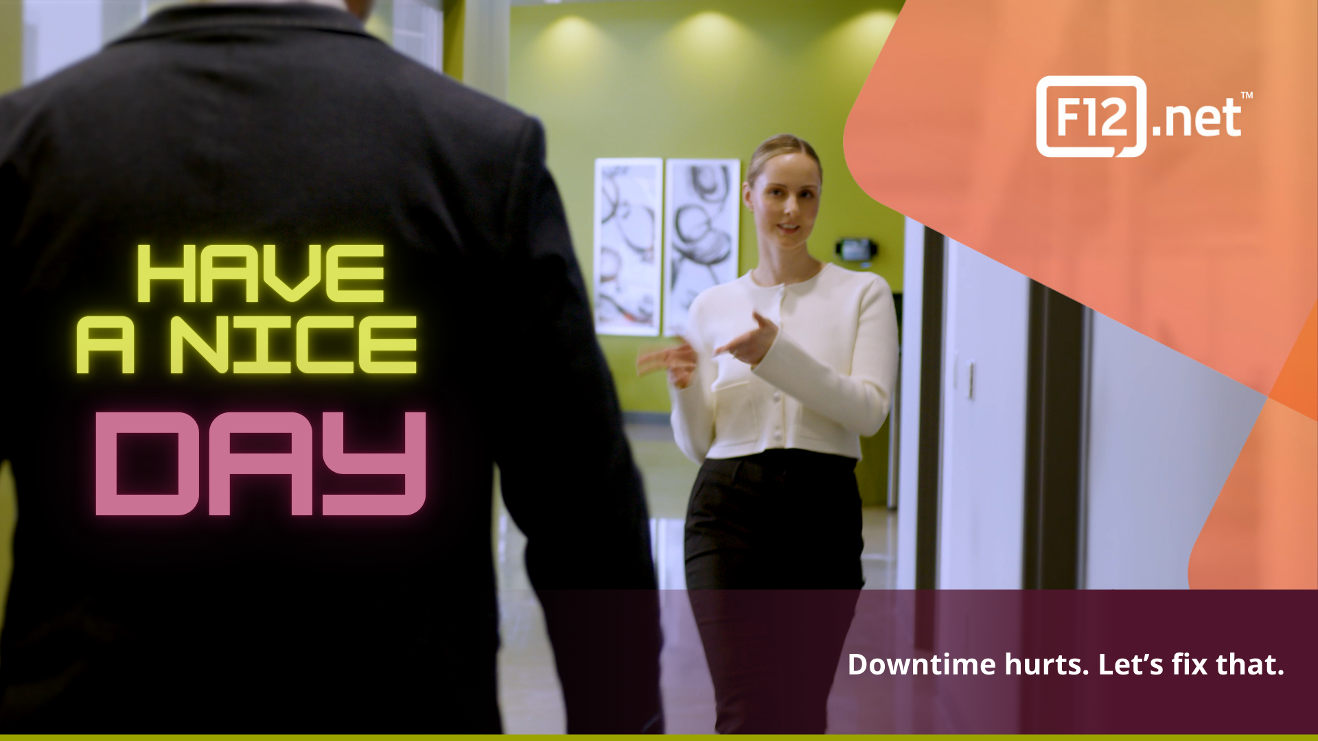 F12.net – Have a Nice Day | Managed Services that Reduce Downtime Smiling businesswoman greeting colleague in hallway with “Have a Nice Day” neon text overlay – F12.net Managed Services.